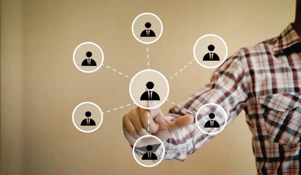 Person pointing at a network of connected icons, symbolizing connections or referrals.